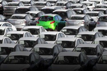 a parking lot of cars in black and white with one green car.jpg